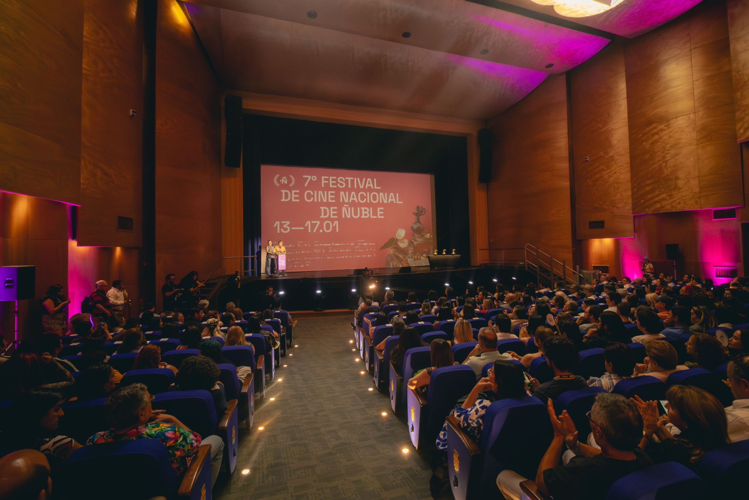 Público en una sala de teatro frente a una pantalla que anuncia el séptimo Festival de Cine Nacional de Ñuble.
